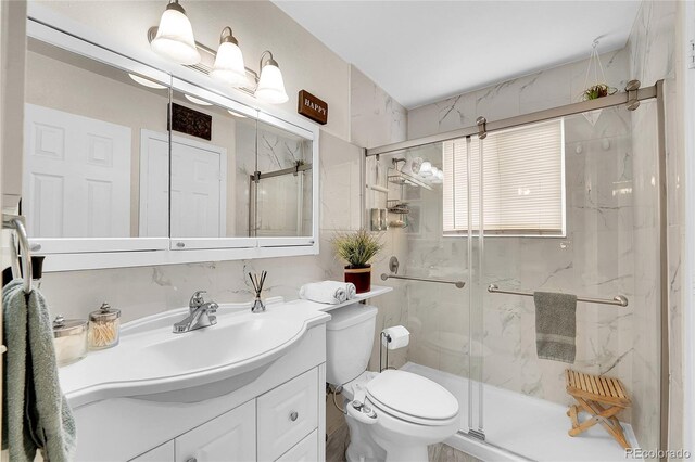 full bath with a marble finish shower, toilet, and vanity