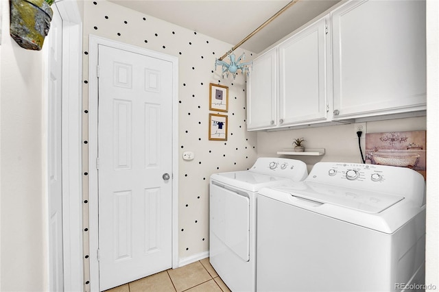 clothes washing area with washer and dryer, cabinet space, and light tile patterned flooring