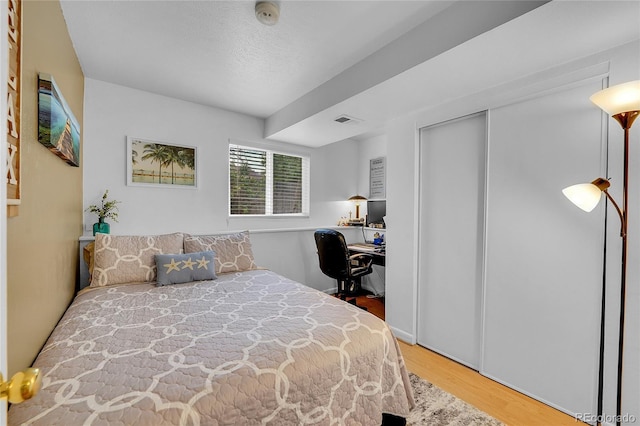 bedroom featuring wood finished floors, an office area, and a closet