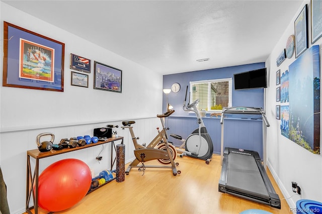 exercise area with wood finished floors and wainscoting