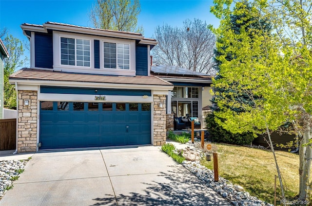 view of front facade with an attached garage, a front lawn, stone siding, concrete driveway, and solar panels
