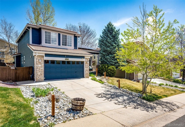 view of front facade with fence, an attached garage, driveway, and stone siding