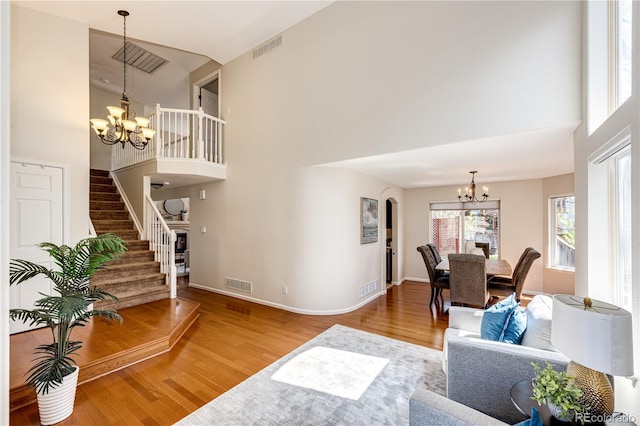 living room featuring a high ceiling, an inviting chandelier, wood finished floors, and visible vents