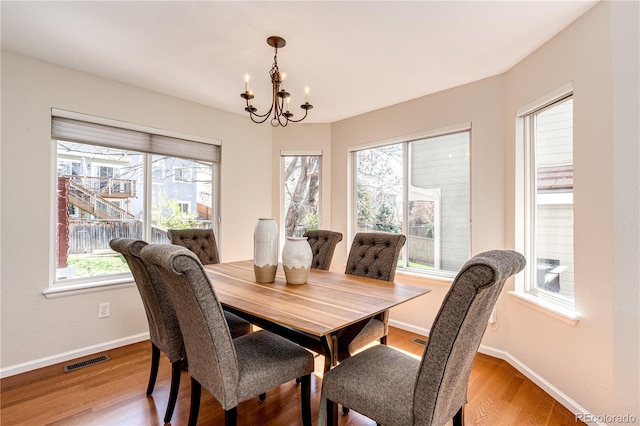 dining space with baseboards, visible vents, wood finished floors, and a chandelier