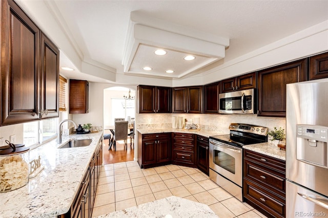 kitchen with a sink, arched walkways, light tile patterned floors, and stainless steel appliances