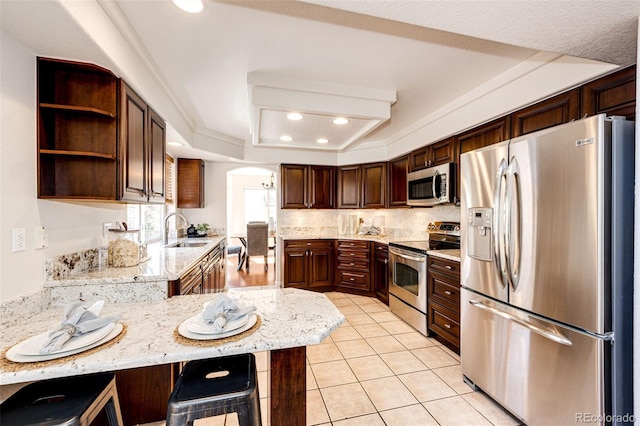 kitchen with arched walkways, a sink, light tile patterned floors, a peninsula, and stainless steel appliances