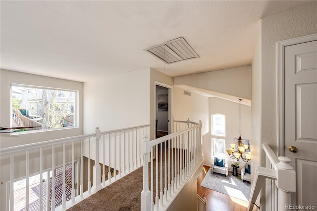 hall featuring a chandelier, an upstairs landing, a healthy amount of sunlight, and visible vents