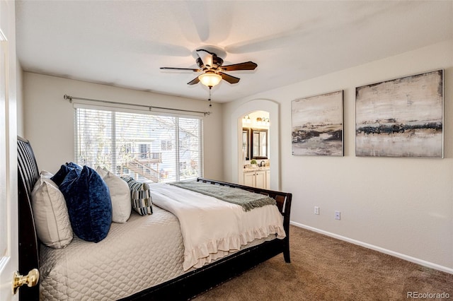 carpeted bedroom featuring arched walkways, baseboards, a ceiling fan, and ensuite bathroom