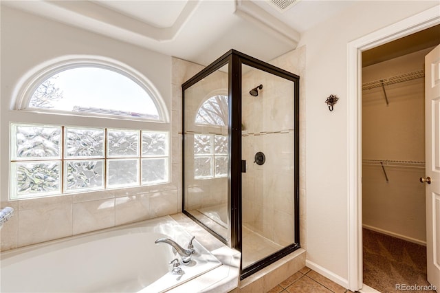 bathroom featuring a walk in closet, tile patterned floors, a shower stall, visible vents, and a garden tub