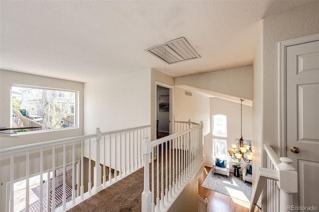 hallway with a wealth of natural light, visible vents, and an upstairs landing