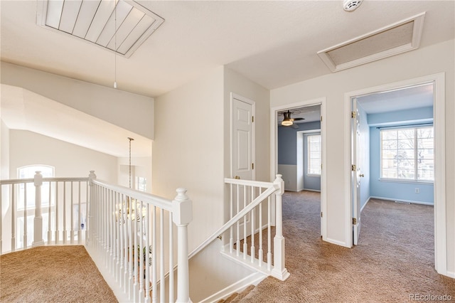 hallway with baseboards, visible vents, carpet flooring, and an upstairs landing