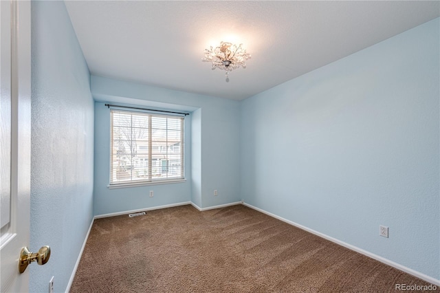 carpeted spare room with visible vents and baseboards