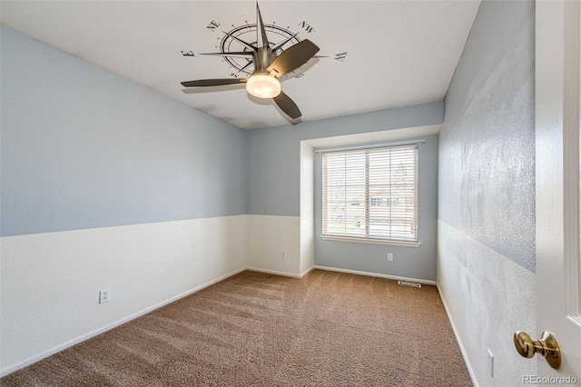 carpeted empty room featuring baseboards, a ceiling fan, and visible vents