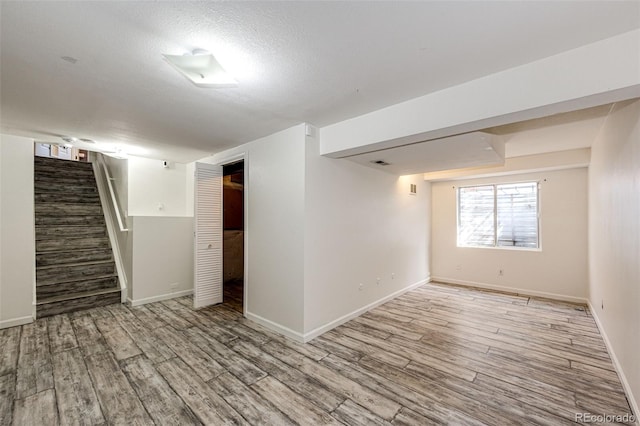 below grade area featuring baseboards, stairs, wood finished floors, and visible vents
