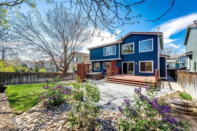 back of property featuring a fenced backyard, a wooden deck, and a lawn