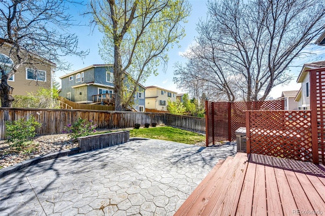 wooden terrace with a fenced backyard, a patio, and a residential view