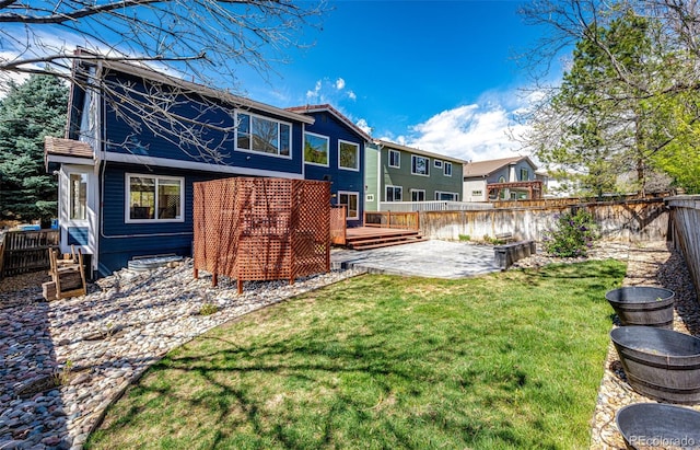rear view of house with a fenced backyard, a patio, a lawn, and a deck