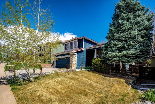 view of front of house with fence, a front lawn, stone siding, a garage, and driveway