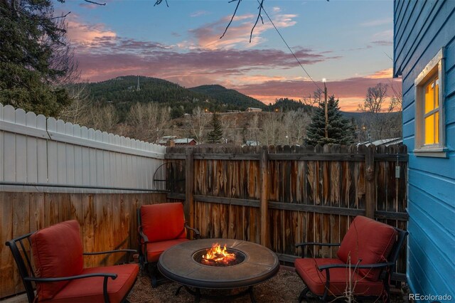 2041 Virginia St, Idaho Springs, CO 80452 - patio terrace at dusk featuring a fire pit, a mountain view, and a fenced backyard