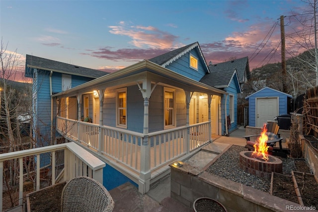 2041 Virginia St, Idaho Springs, CO 80452 - view of front of property featuring an outbuilding, a fire pit, a porch, roof with shingles, and a storage shed