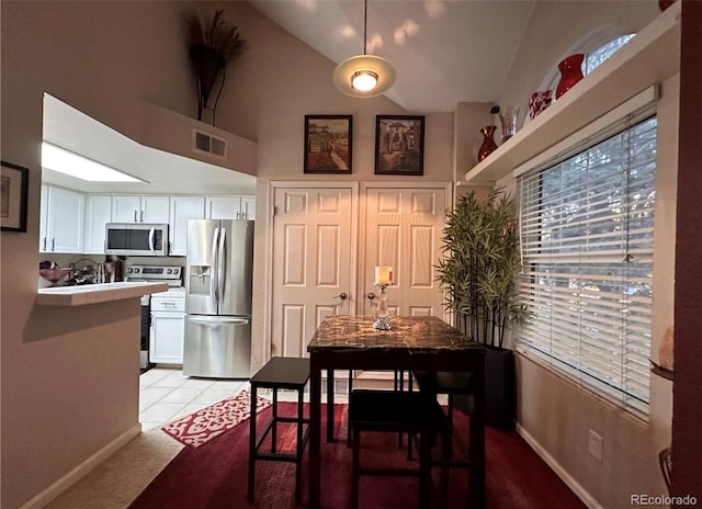 dining room with high vaulted ceiling, baseboards, and light carpet