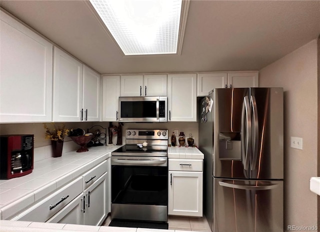 kitchen featuring appliances with stainless steel finishes, tile countertops, and white cabinetry