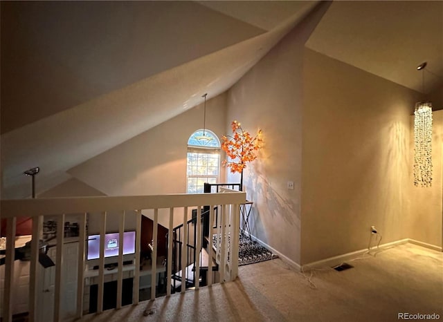 hallway featuring carpet flooring, baseboards, and high vaulted ceiling