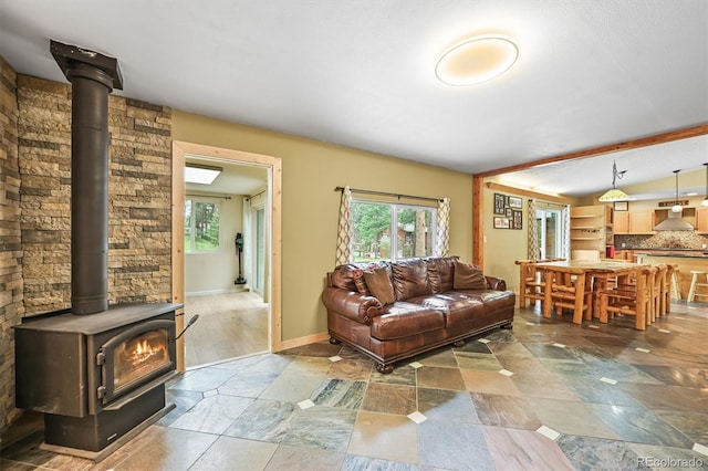 26499 W St, Conifer, CO 80433 - living area featuring a wood stove, vaulted ceiling, and stone finish flooring