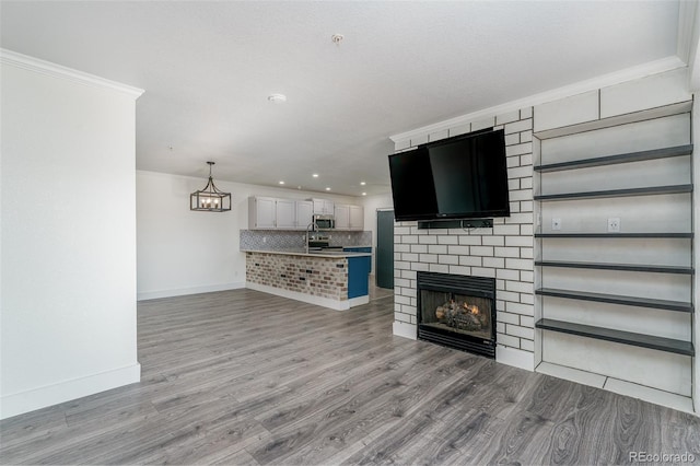 12118 W Dorado Pl Unit 206, Littleton, CO 80127 - unfurnished living room featuring light wood-style floors, ornamental molding, a chandelier, recessed lighting, and a large fireplace