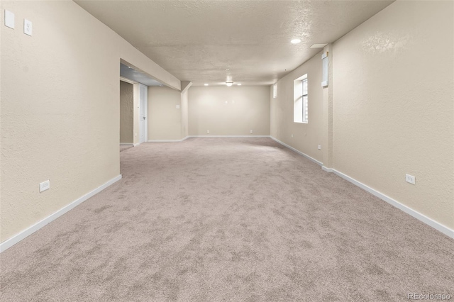 below grade area with a textured wall, baseboards, carpet flooring, and a textured ceiling