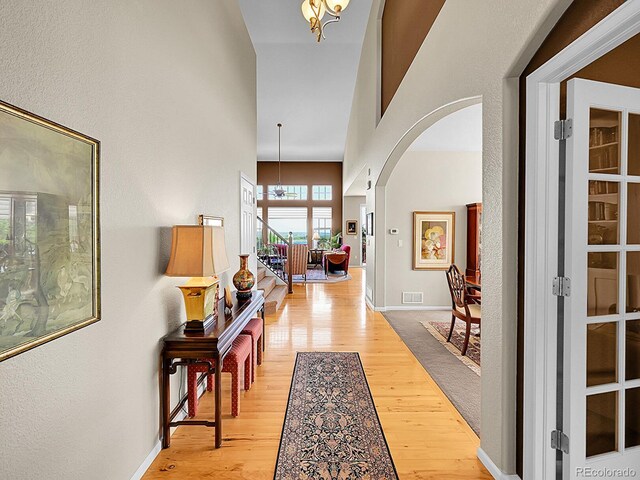 10565 Kicking Horse Dr, Littleton, CO 80125 - entrance foyer featuring light wood-style floors, a chandelier, arched walkways, and a towering ceiling