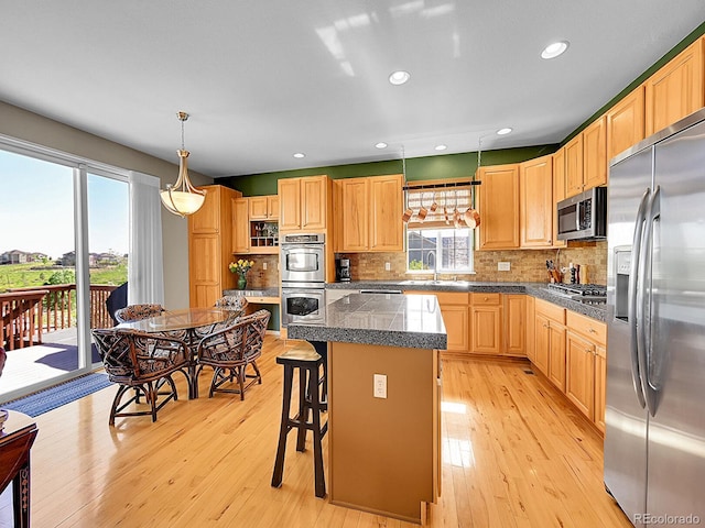 10565 Kicking Horse Dr, Littleton, CO 80125 - kitchen with stainless steel appliances, a kitchen island, light wood-type flooring, decorative backsplash, and recessed lighting