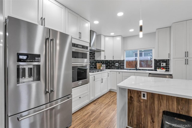 kitchen featuring sink, stainless steel appliances, white cabinets, and wall chimney exhaust hood