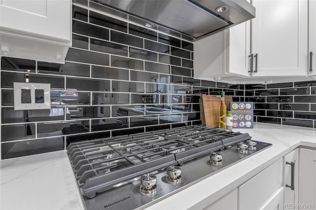 details featuring backsplash, stainless steel gas cooktop, light stone counters, and white cabinets