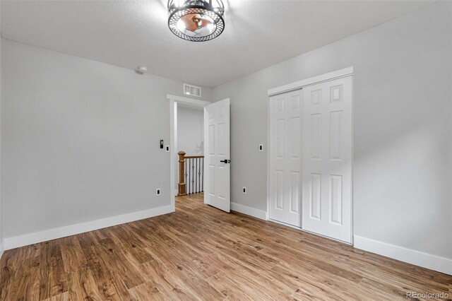 unfurnished bedroom featuring a closet, visible vents, light wood-style flooring, and baseboards