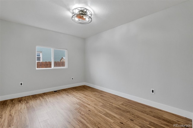 spare room featuring visible vents, baseboards, and wood finished floors