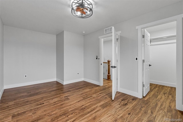 unfurnished bedroom featuring dark hardwood / wood-style flooring, a walk in closet, and a closet