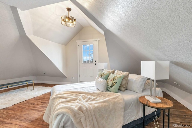 bedroom with dark wood-type flooring, lofted ceiling, and a textured ceiling