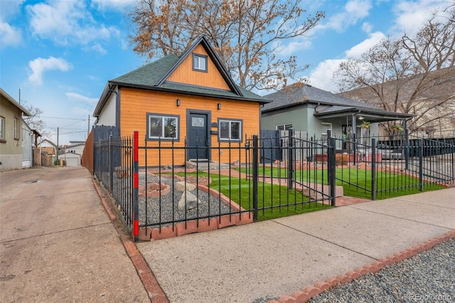 view of front of house with a fenced front yard, a shingled roof, and a front lawn