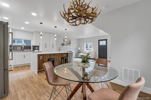 dining area featuring visible vents, light wood-style flooring, recessed lighting, a fireplace, and baseboards