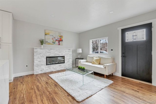 living room with visible vents, a fireplace, baseboards, and light wood-style floors