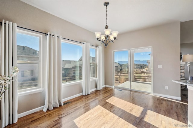 unfurnished dining area with a notable chandelier, a wealth of natural light, and light hardwood / wood-style flooring