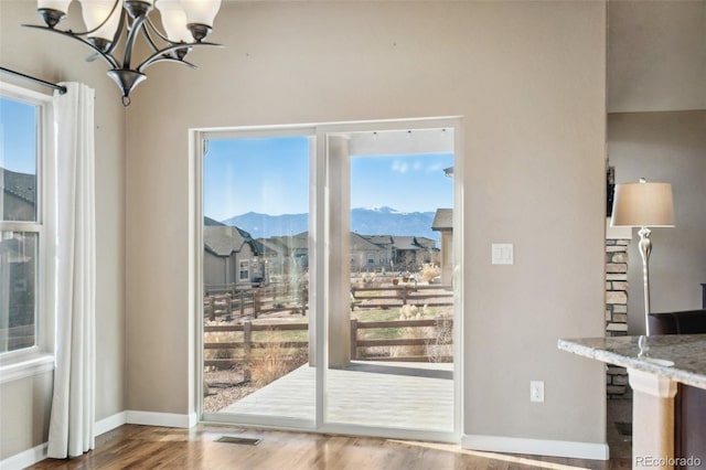 doorway to outside featuring a notable chandelier, a mountain view, and wood-type flooring