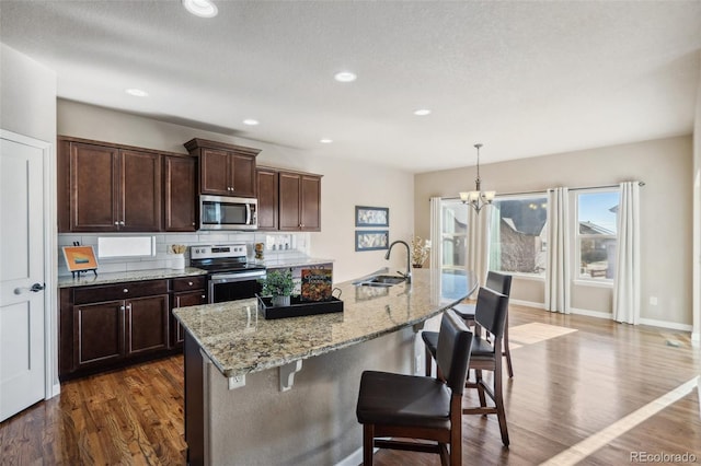 kitchen with sink, stainless steel appliances, a notable chandelier, pendant lighting, and decorative backsplash