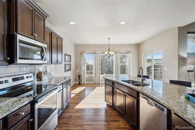 kitchen featuring light stone countertops, sink, hanging light fixtures, stainless steel appliances, and a chandelier