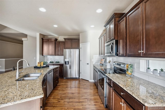 kitchen featuring sink, dark hardwood / wood-style floors, light stone countertops, tasteful backsplash, and stainless steel appliances