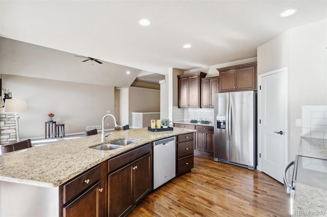 kitchen featuring ceiling fan, sink, stainless steel appliances, decorative backsplash, and a kitchen island with sink