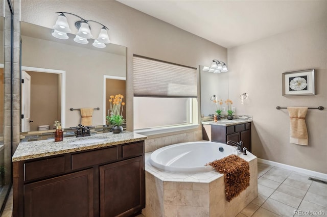 bathroom with tile patterned flooring, vanity, and tiled tub