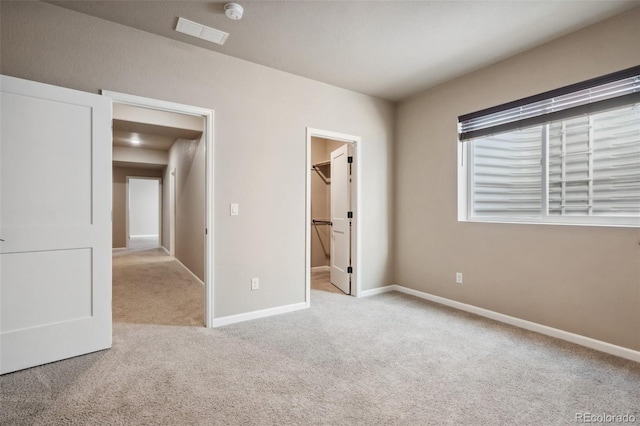 unfurnished bedroom with a walk in closet, light carpet, and a closet