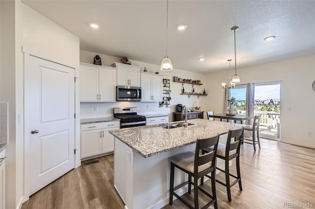 7702 E 159th Ave, Thornton, CO 80602 - kitchen with stainless steel appliances, a sink, backsplash, light wood-style floors, and white cabinetry